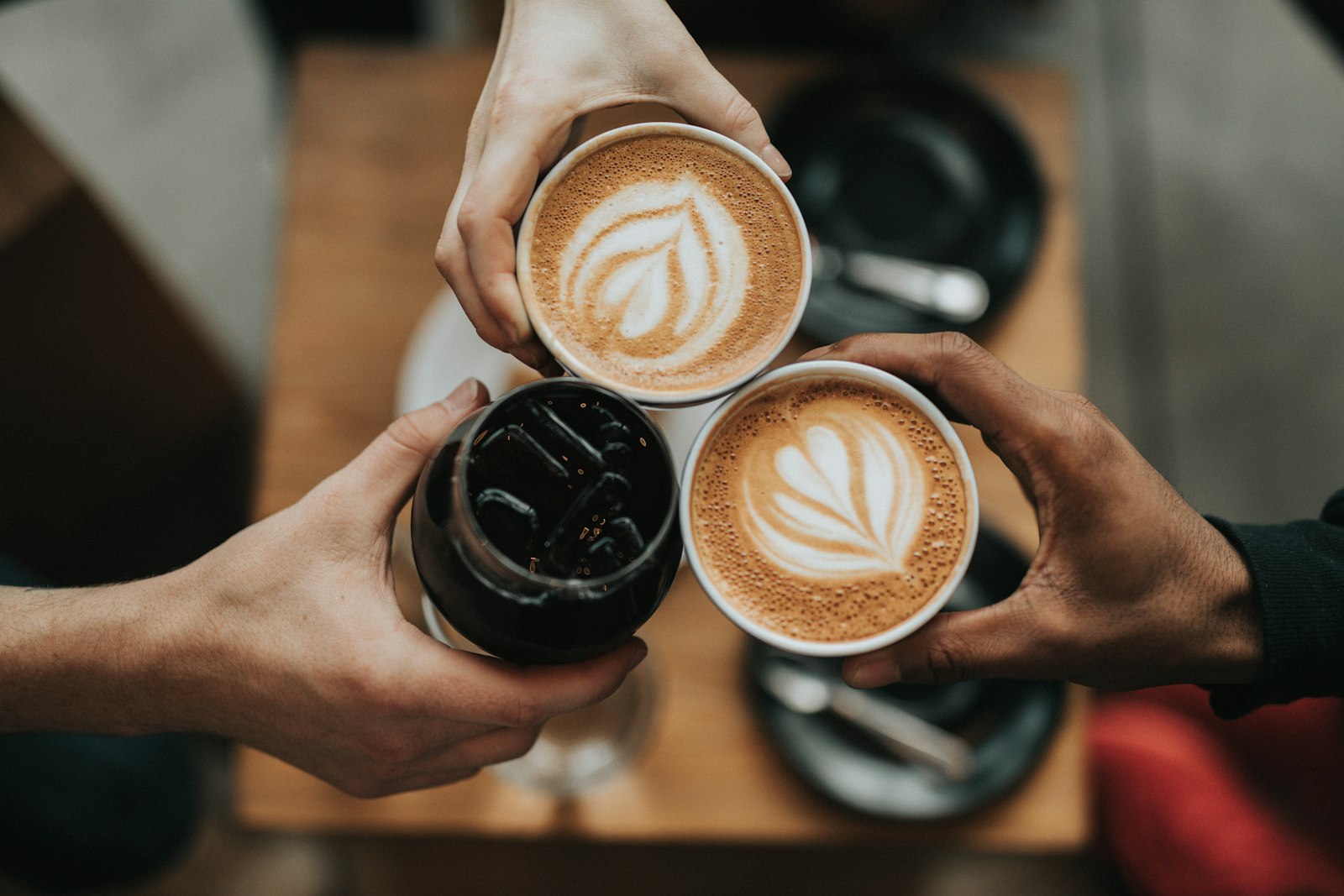 A cup of filter coffee on a wooden table next to a glass kettle